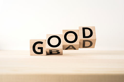 Scrabble wooden letter tiles spelling out the words "good" and "bad" on a neutral background, symbolising moral choices and human nature.